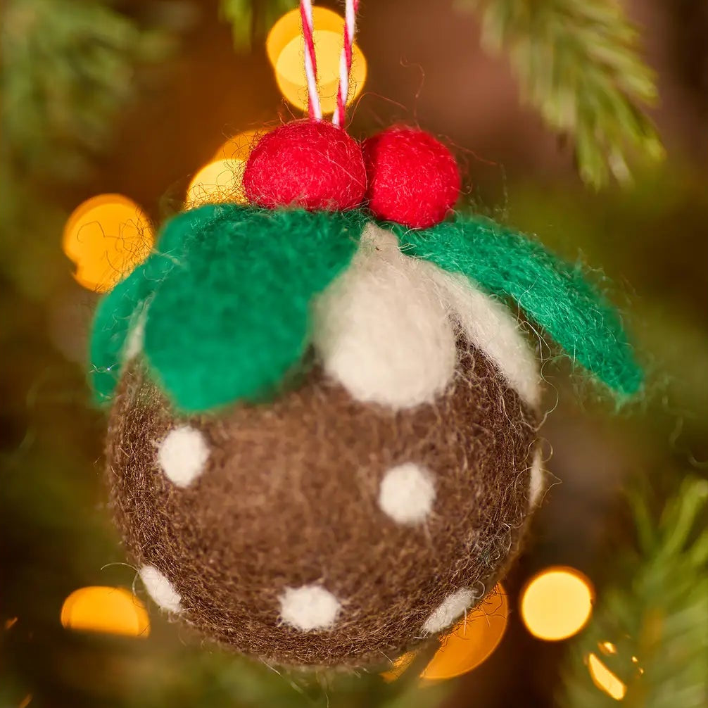 Felted Christmas pudding ornament on a tree with blurred lights in the background