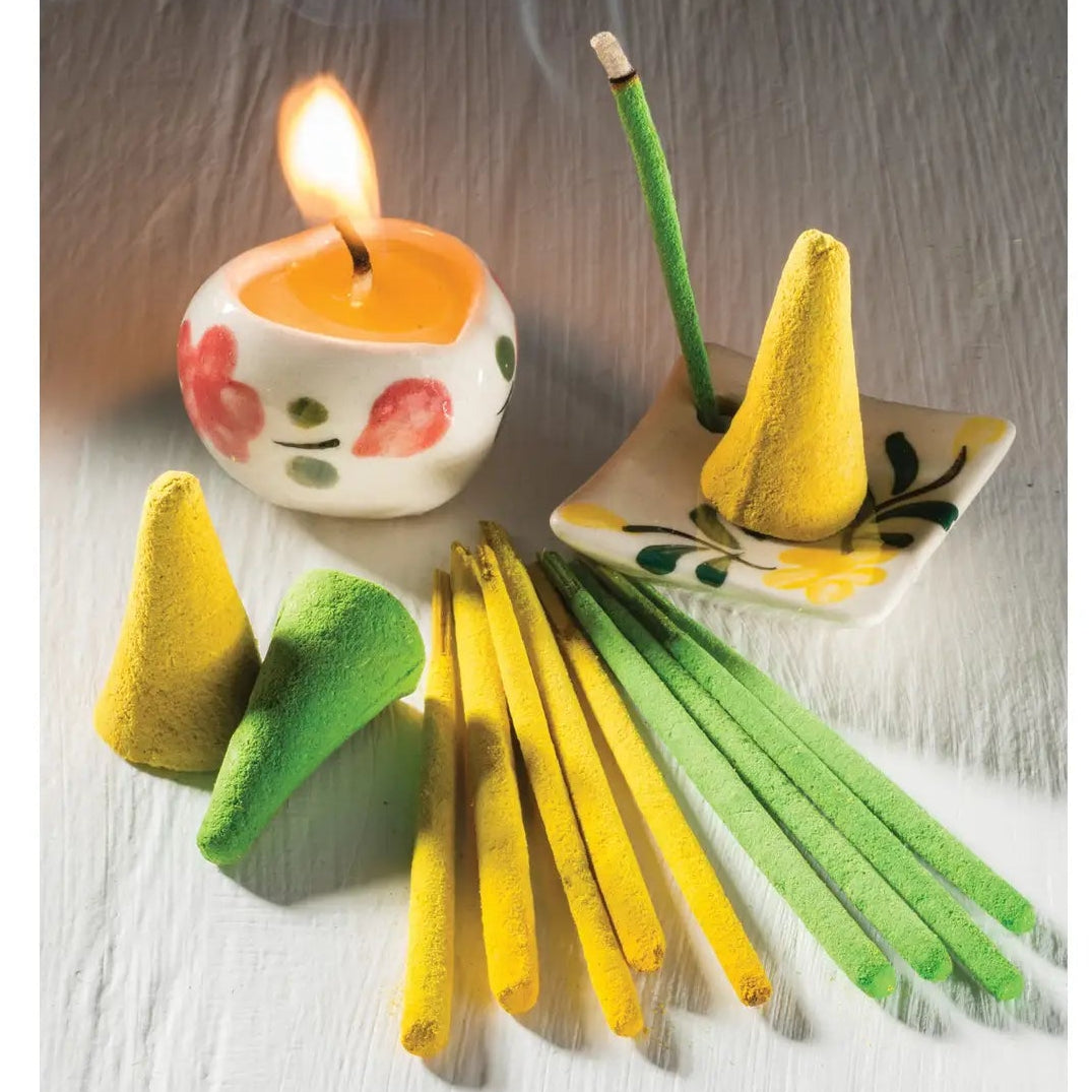 Incense cones and sticks with a lit candle on a wooden surface